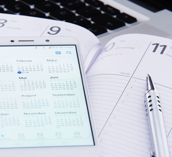 Ein Kalender auf einem Smarphone und ein Terminklender in gedruckter Form ist zu sehen.